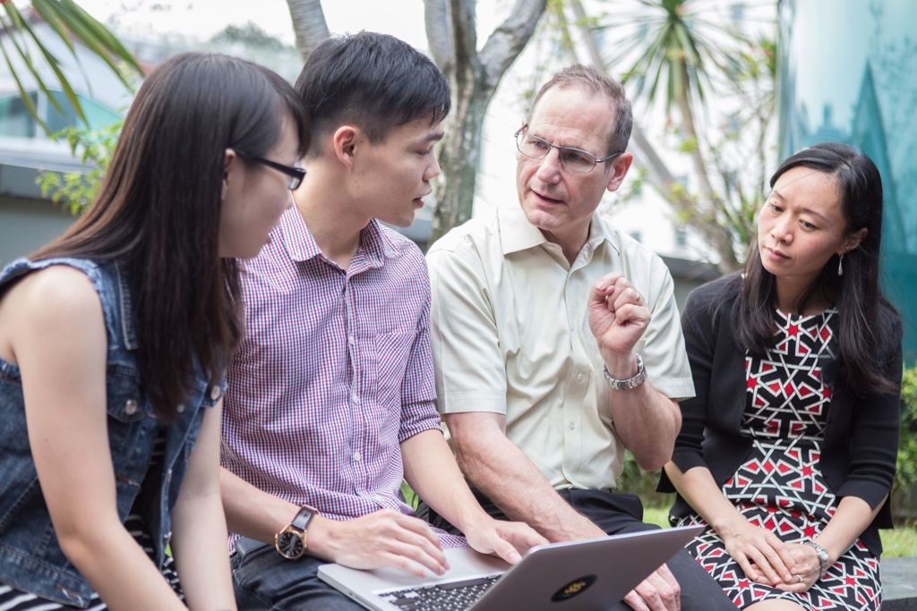 Miniature of Professor Steven Miller engaging three students in a small group discussion