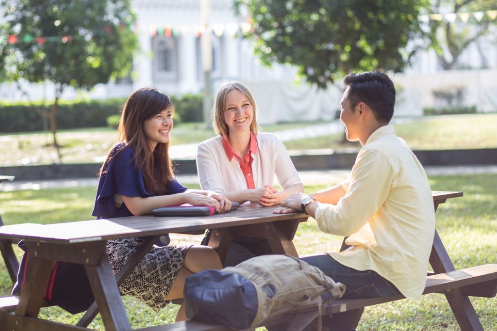 Miniature of Professor Amanda Jakobsson having a discussion with two students in a bench next to Campus Green