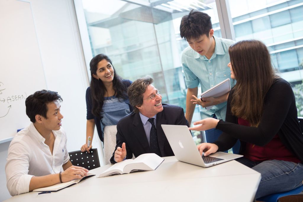 Miniature of Students having small group discussions with Professor Basil Bitas in a classroom